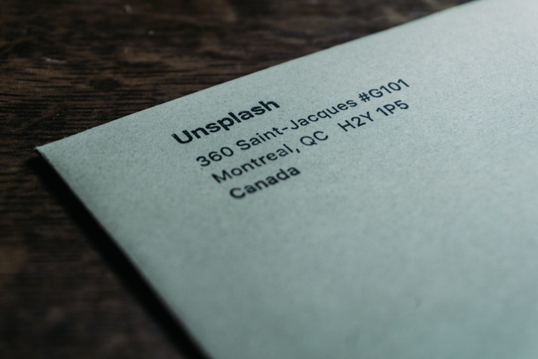 Close-up of a pale blue envelope on a dark wooden surface, showing the text 'Unsplash' and an address in Montréal, QC, Canada.