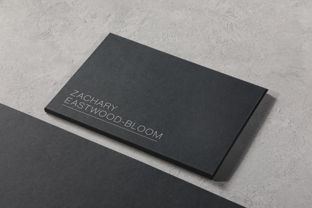 Dark gray business card with the name Zachary Eastwood-Bloom on a textured gray surface.