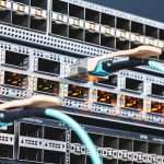 Rack of network switches with glowing orange port LEDs and blue Ethernet cables plugged in