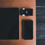 Tablet and smartphone with a small black accessory labeled 'VUKIT' on a wooden desk surface.