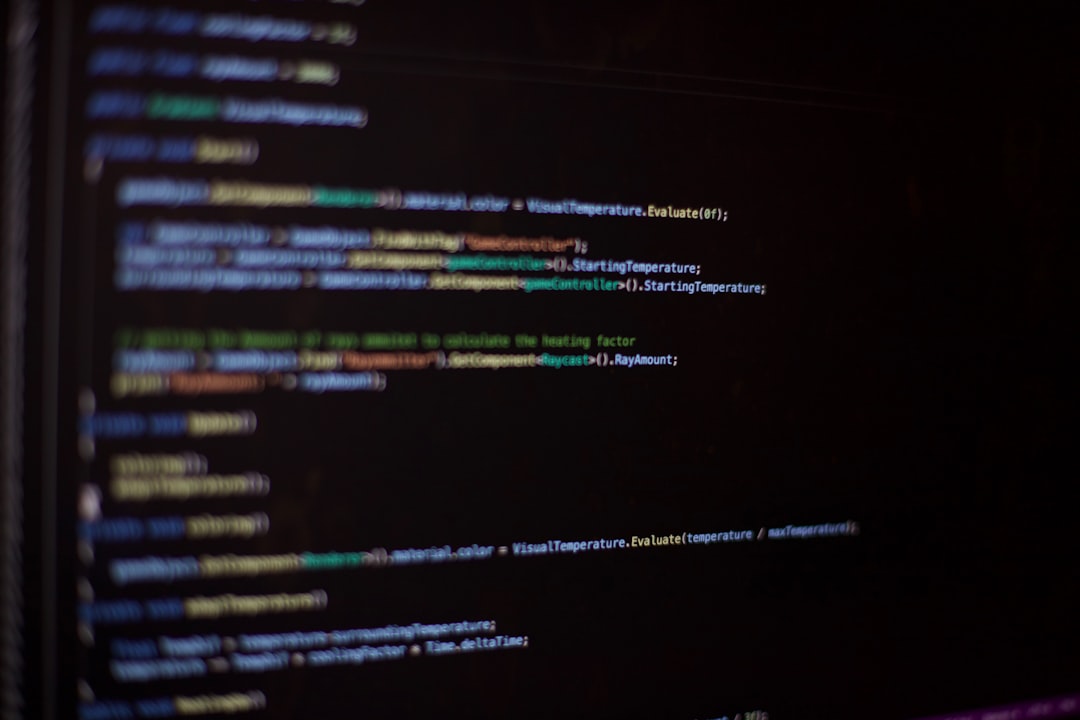 Dark monitor showing colorful, blurred lines of code in a coding environment.