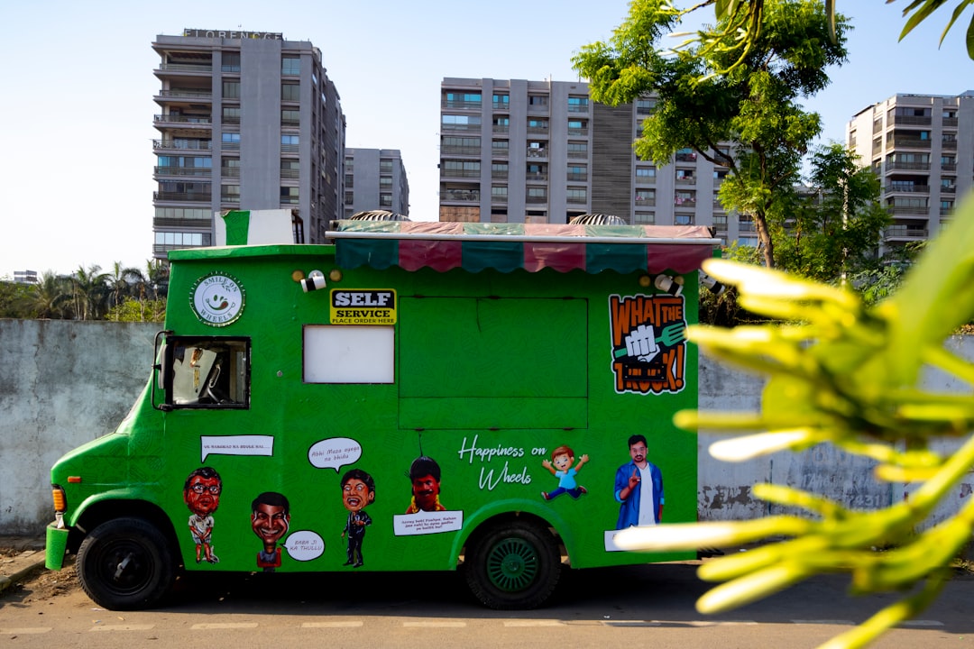 Green food truck with cartoon characters and 'Happiness on Wheels' text, set against urban high-rise buildings.