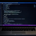 Laptop with a dark code editor open, showing C# code in Unity project.