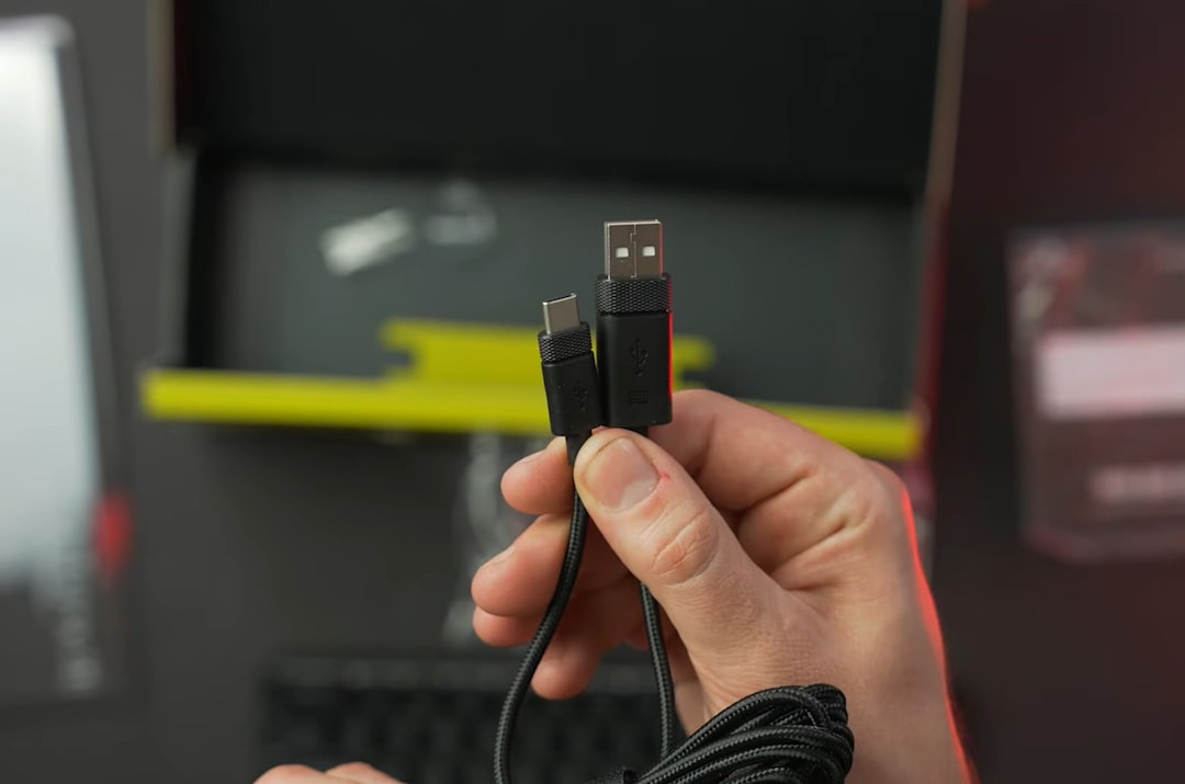 Hand holding a braided cable with USB-C and USB-A connectors, ready for charging/data transfer