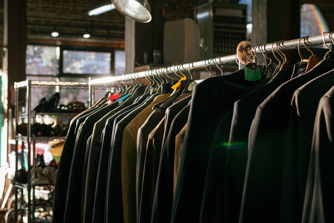 Row of dark jackets hanging on a metal clothing rack inside a store.