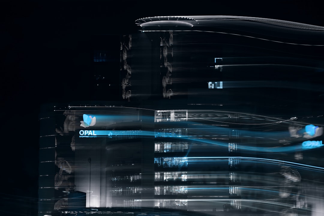 Night cityscape with neon light trails streaking across tall buildings, creating a futuristic blur effect near an Opal Shopping Center sign.