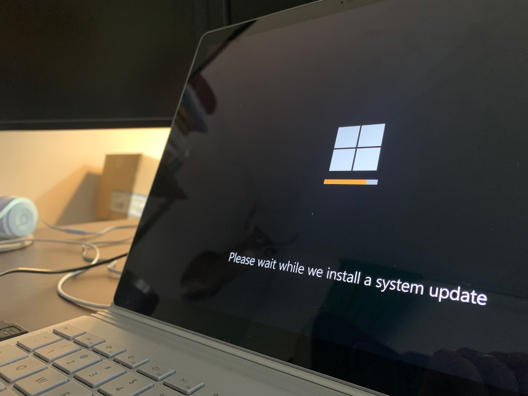 Laptop screen displaying a Windows update in progress with a progress bar and the message: 'Please wait while we install a system update'.