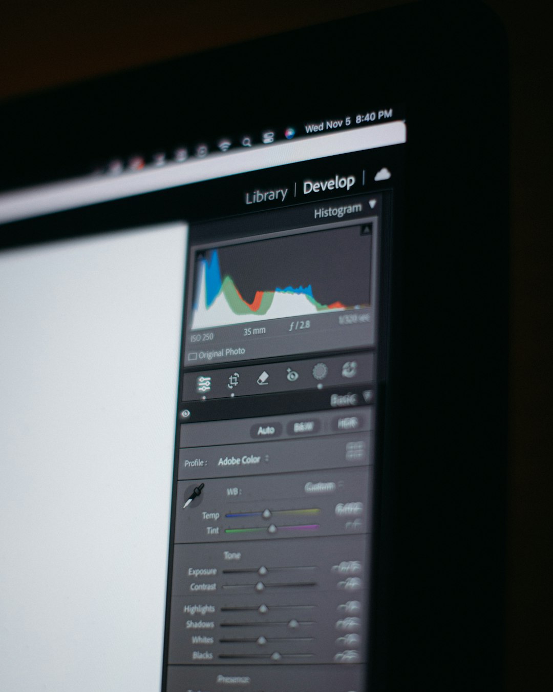 Close-up of a computer screen displaying a photo editing interface with histogram and editing sliders in a tilted view.