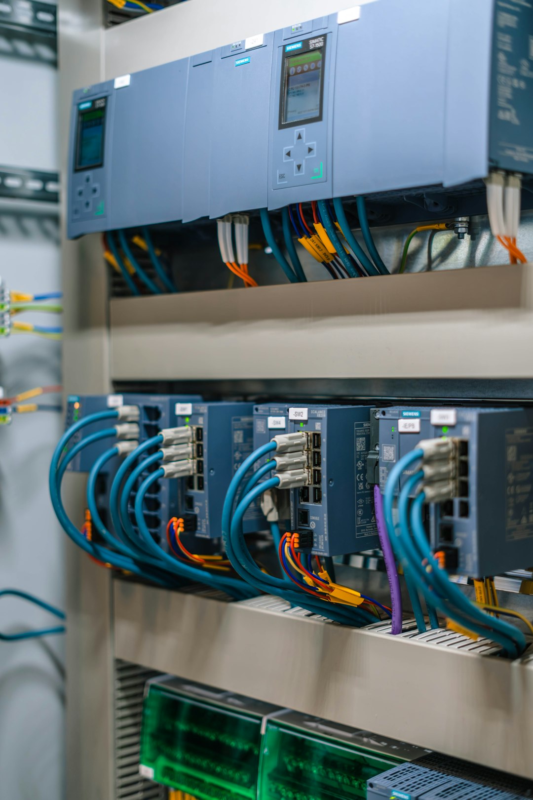 Industrial control cabinet with Siemens PLC modules and a tangle of blue cables.