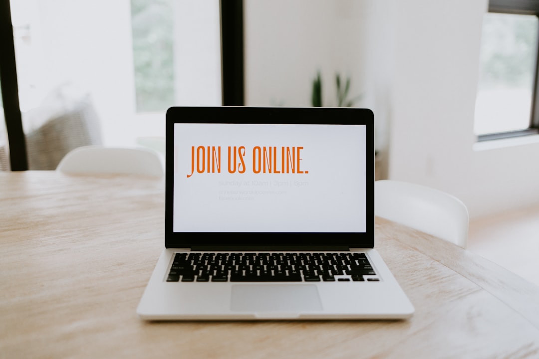 Laptop on a wooden table displaying the message 'Join Us Online' on its screen.