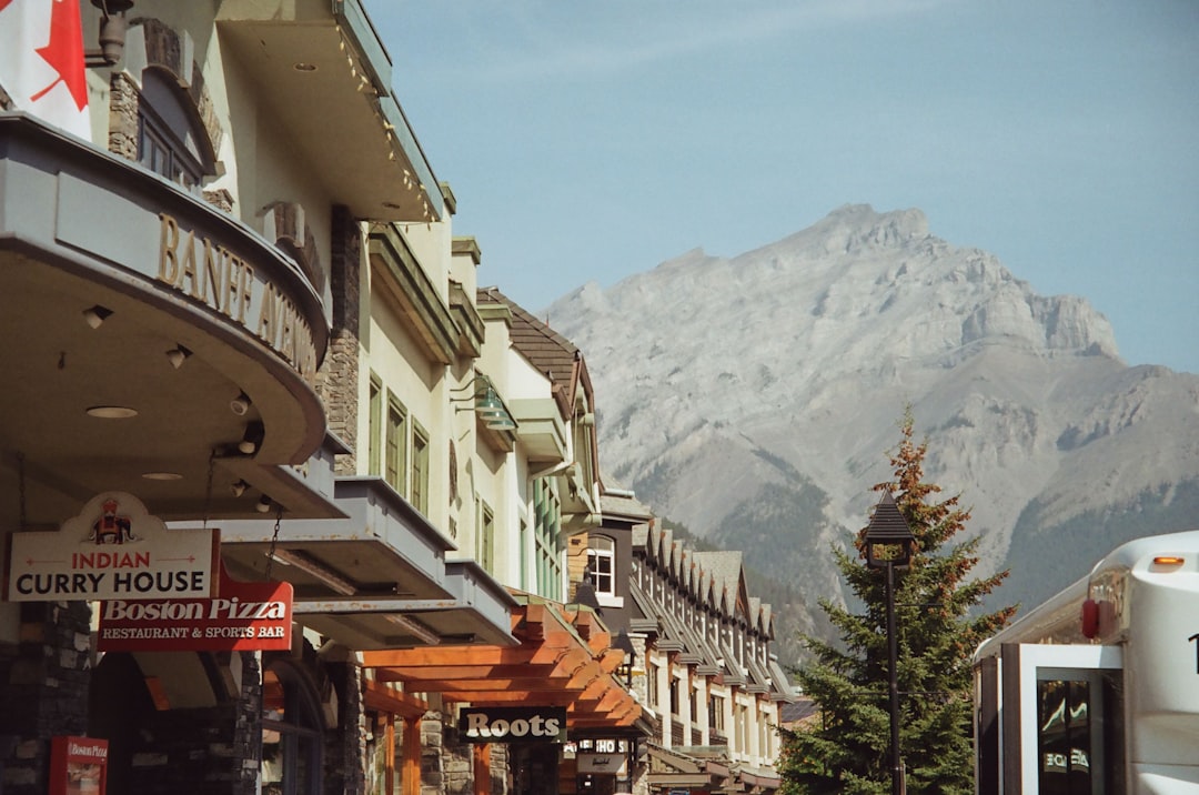 Alpine-looking shopping street with colorful storefronts and signs, mountains in the distance.