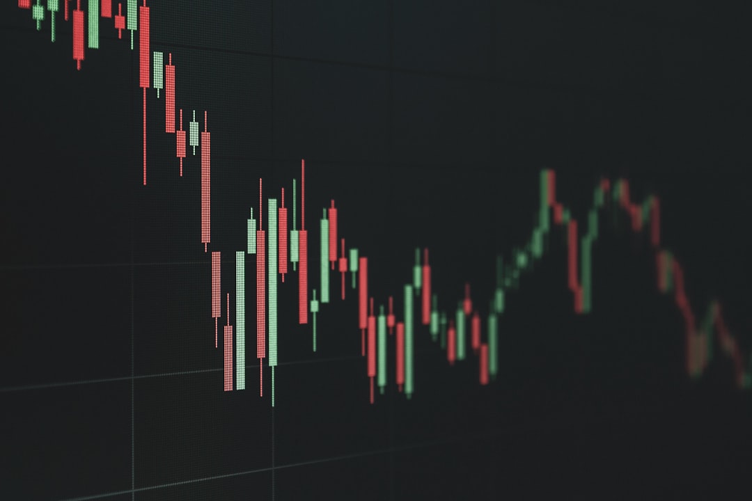 Candlestick chart on a dark background showing fluctuating red and green bars representing price movements in a market graph.