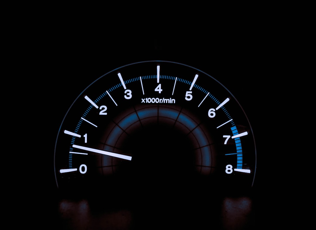 Illuminated car tachometer at night, showing RPM around 0.8 × 1000 r/min with a blue scale and white needles.