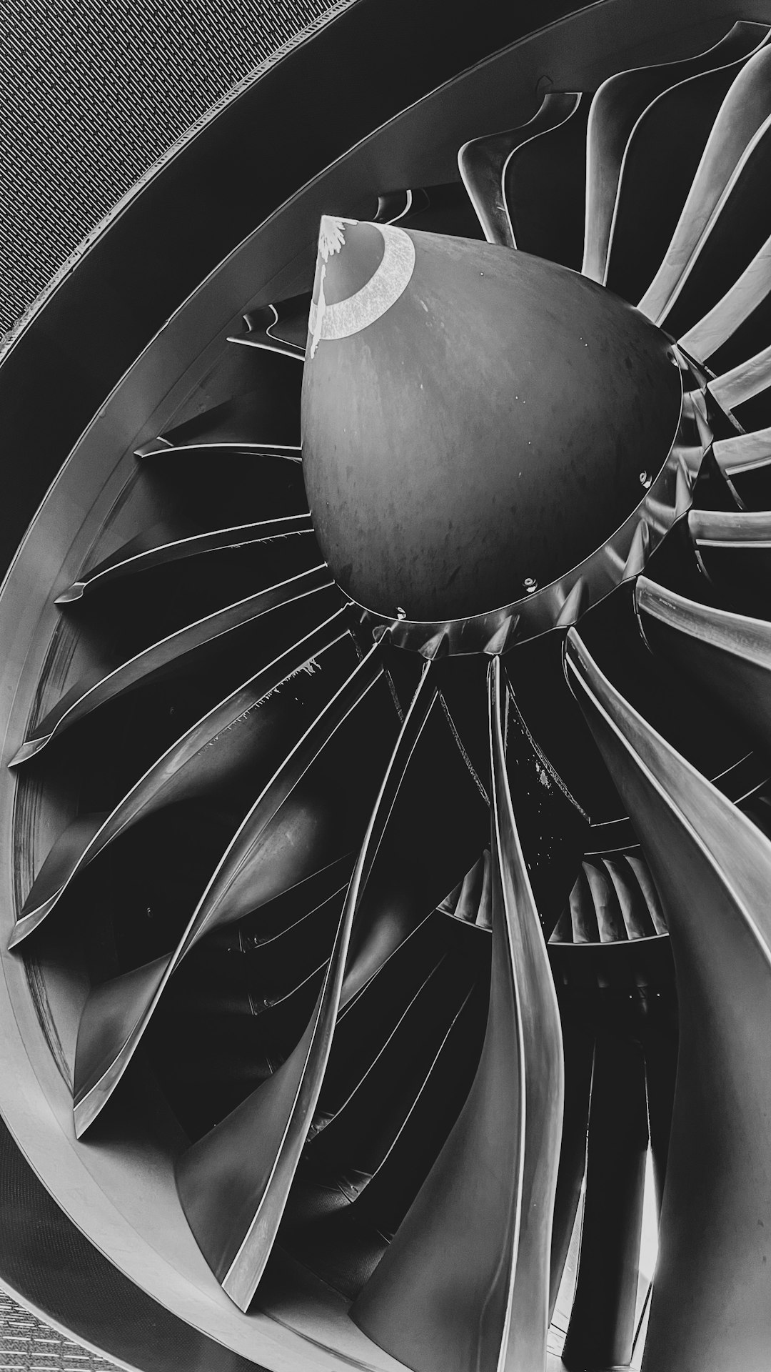Close-up of a large jet engine turbine with curved blades in grayscale (monochrome).