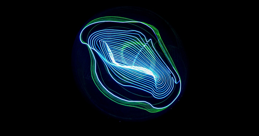 Abstract neon light swirl forming concentric loops in blue and green on a black background, like light painting art.