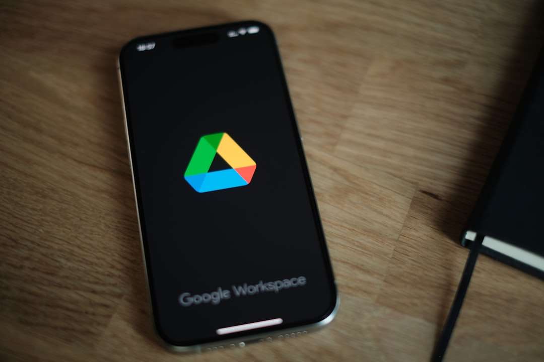 Smartphone on a wooden desk showing Google Workspace logo on the screen.
