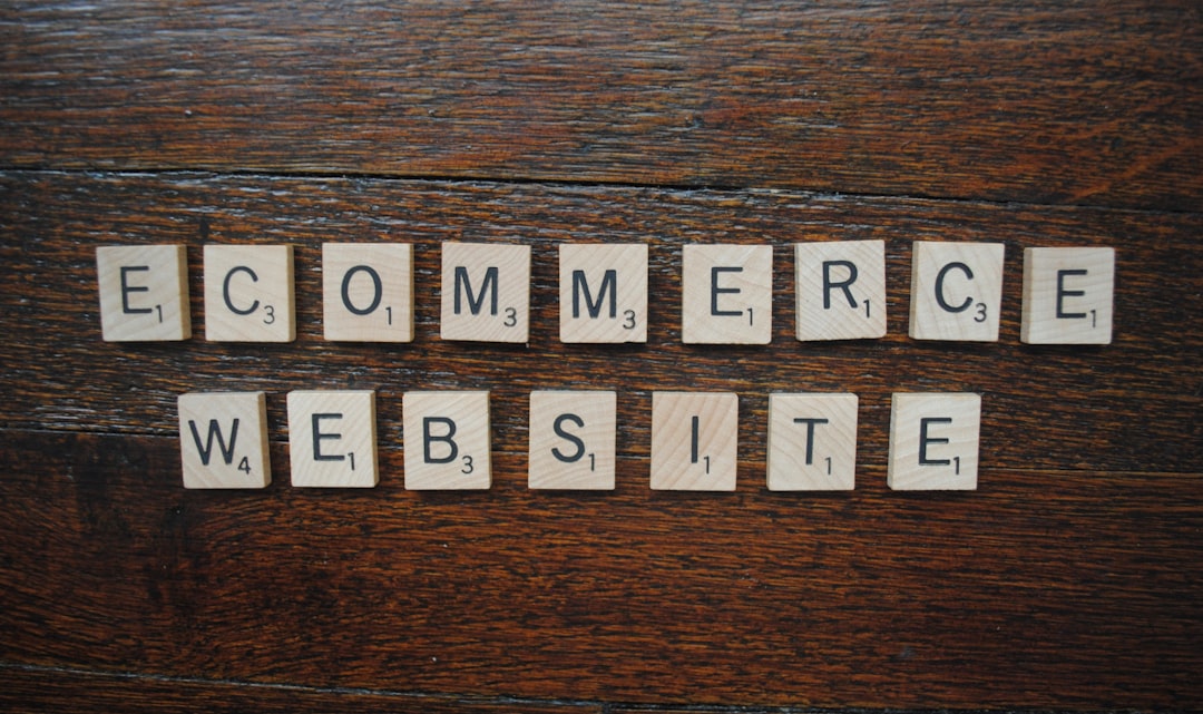 Scrabble tiles spell 'ECOMMERCE WEBSITE' on a dark wooden table, illustrating online shopping concepts.