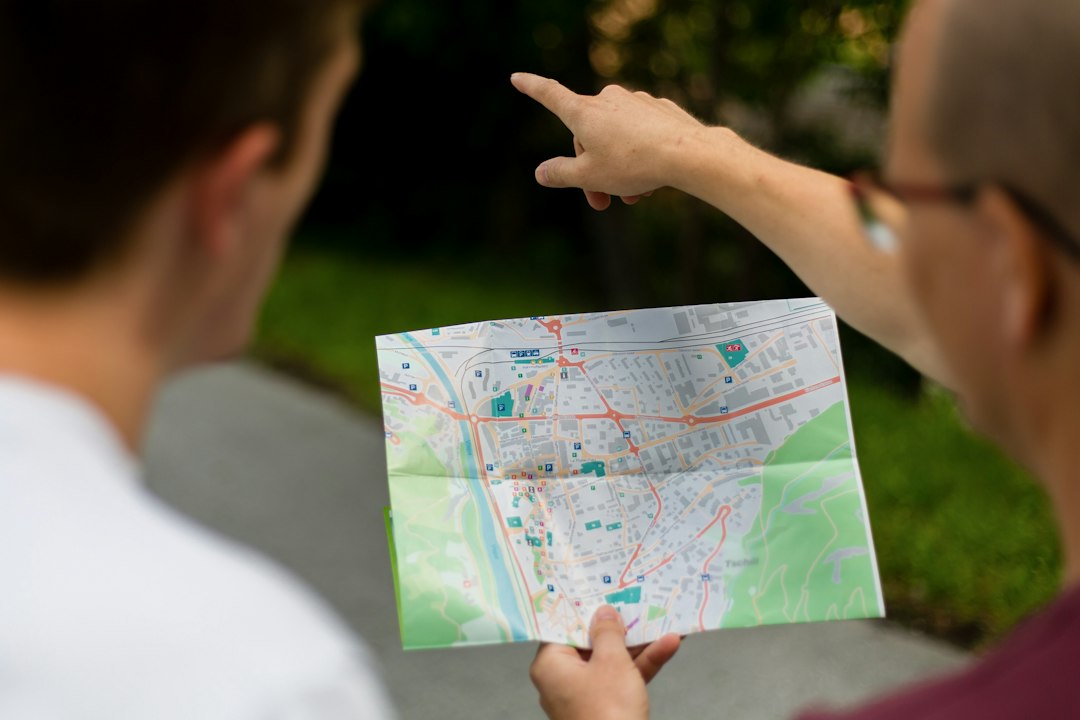 Two people outdoors study a folded city map; one points toward a route.