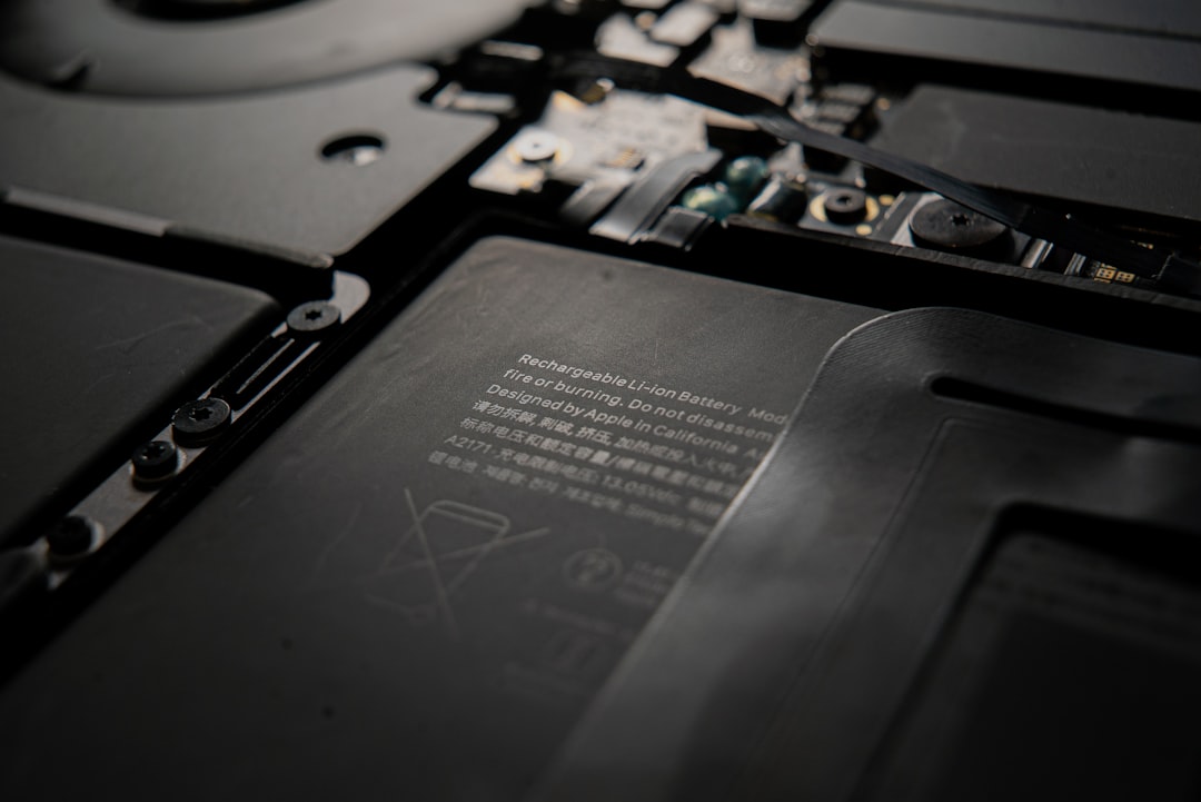 Close-up of a laptop battery inside its compartment, showing warning text and internal circuitry (Li‑ion battery).
