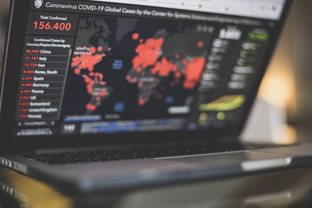 Laptop screen shows a COVID-19 statistics dashboard with a world map marked by red outbreak points and a left sidebar listing country-by-country confirmed cases (e.g., 156,400).
