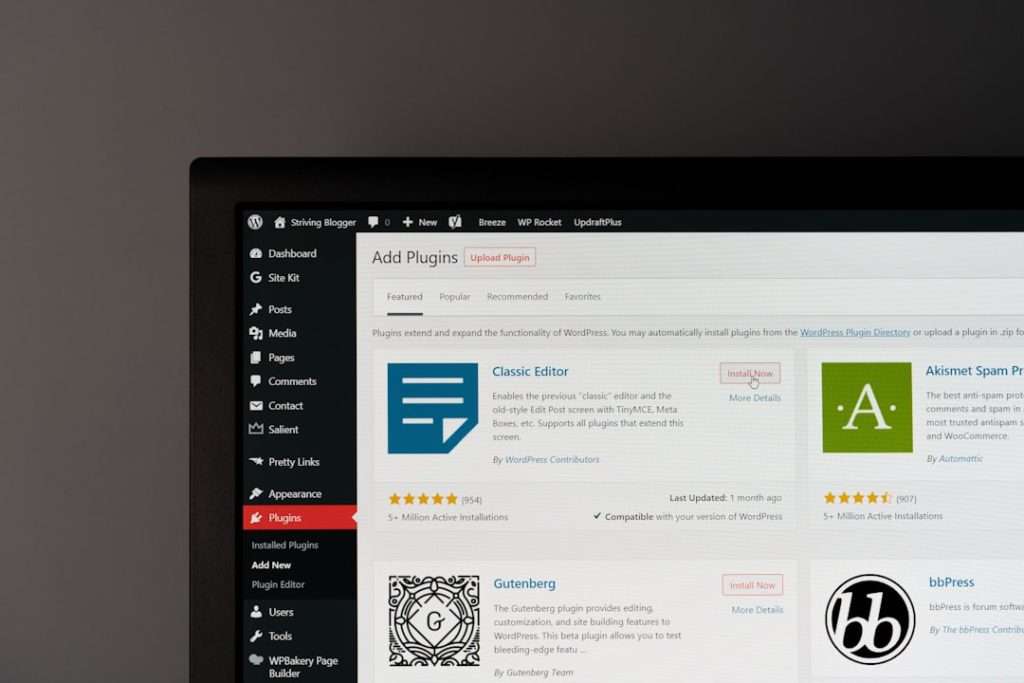 WordPress admin Plugins page on a monitor, showing plugin tiles like Classic Editor and Akismet