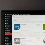 WordPress admin Plugins page on a monitor, showing plugin tiles like Classic Editor and Akismet