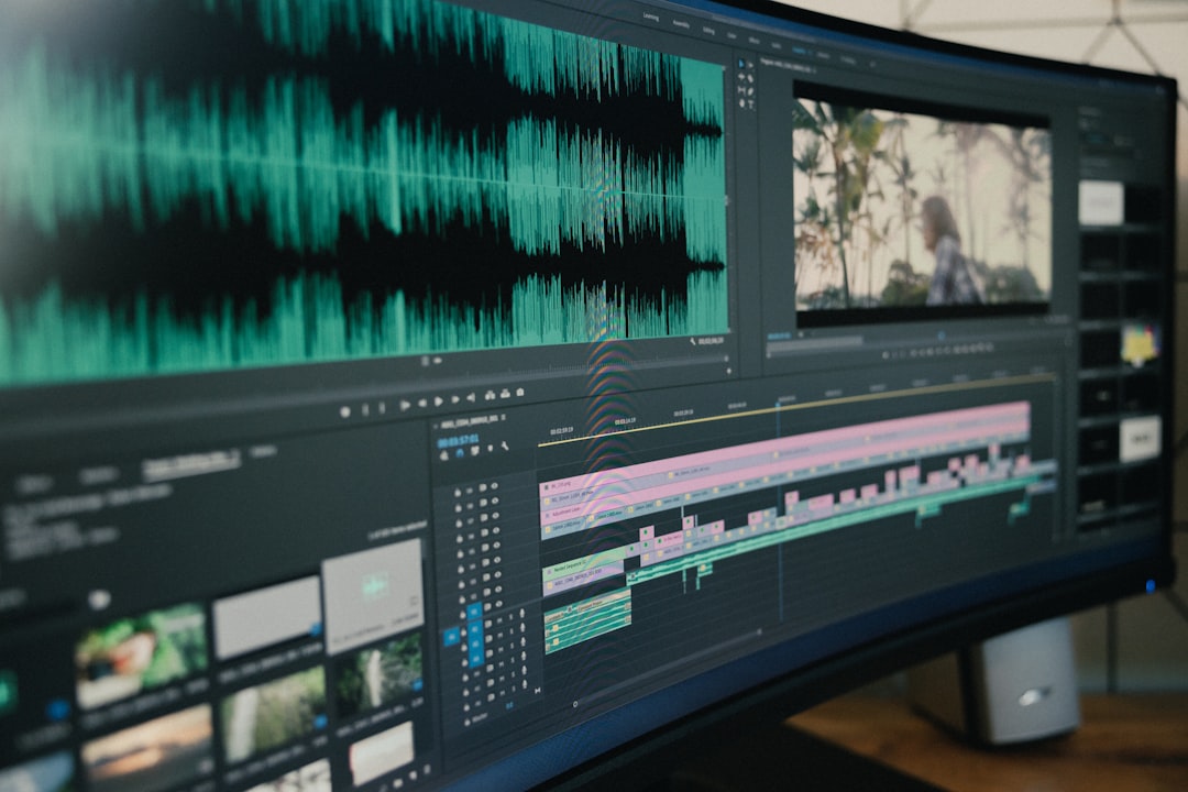 Curved computer monitor showing a video editing workspace with a green audio waveform and a color-coded timeline with clips and previews on screen.