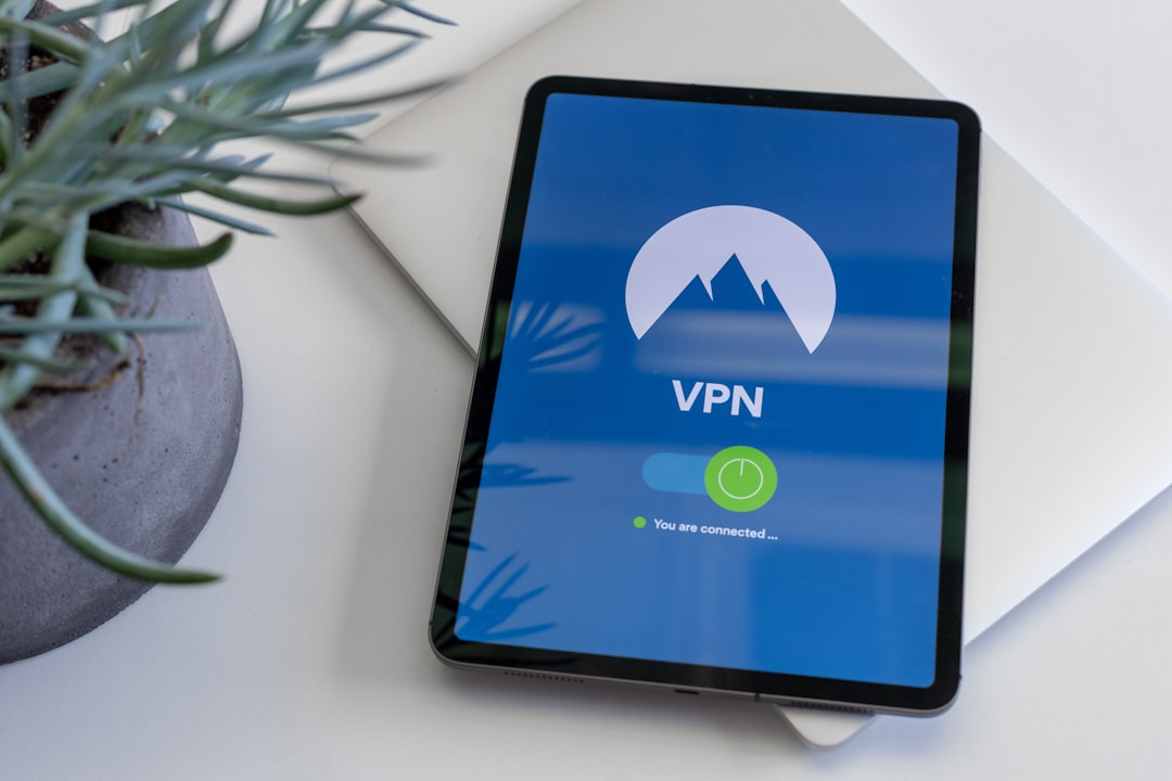 Tablet on a white desk displaying a VPN app with a blue screen, mountain logo, and green connected indicator.