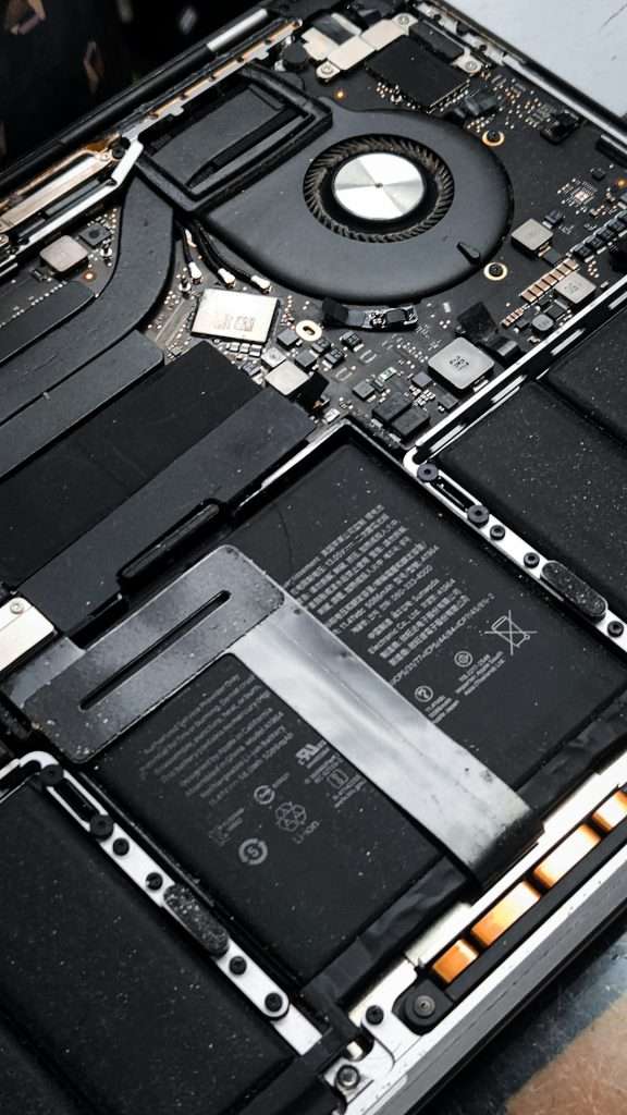 Inside view of a laptop with the bottom shell removed, showing the cooling fan, motherboard, and battery.