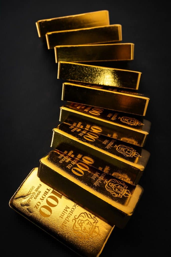 Diagonal stack of shiny gold bars on a dark background, angled in a twisting column.