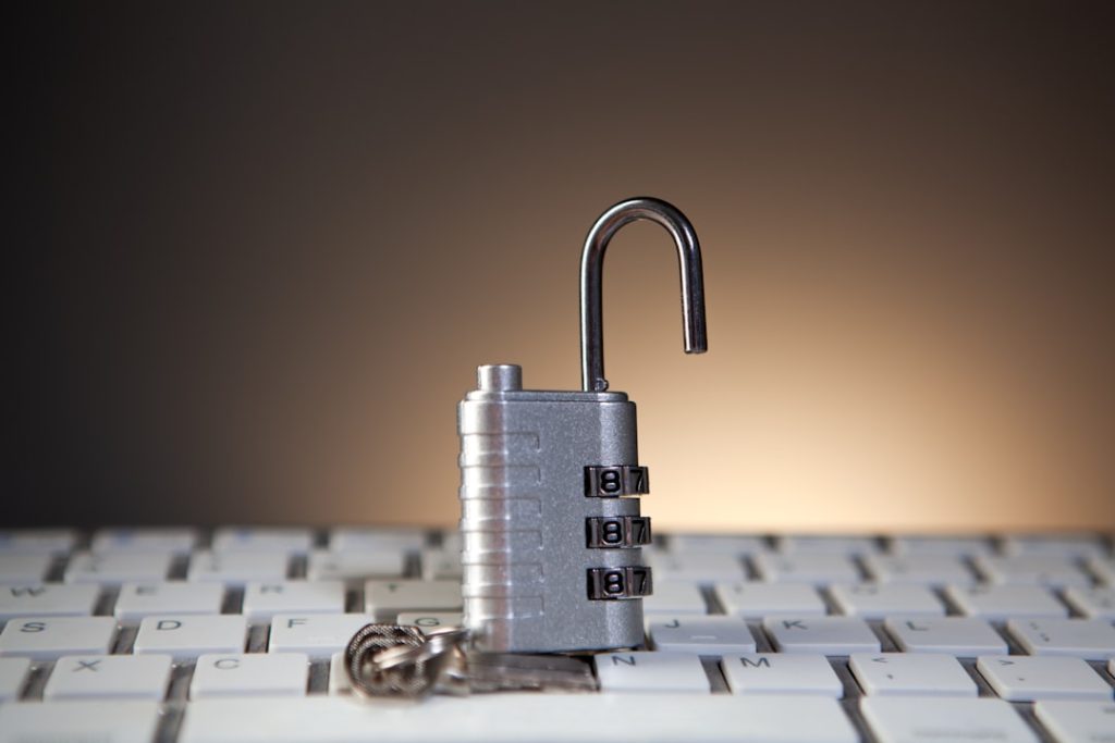 Open metal padlock resting on a computer keyboard, symbolizing cybersecurity and unlocked access.