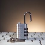 Open metal padlock resting on a computer keyboard, symbolizing cybersecurity and unlocked access.