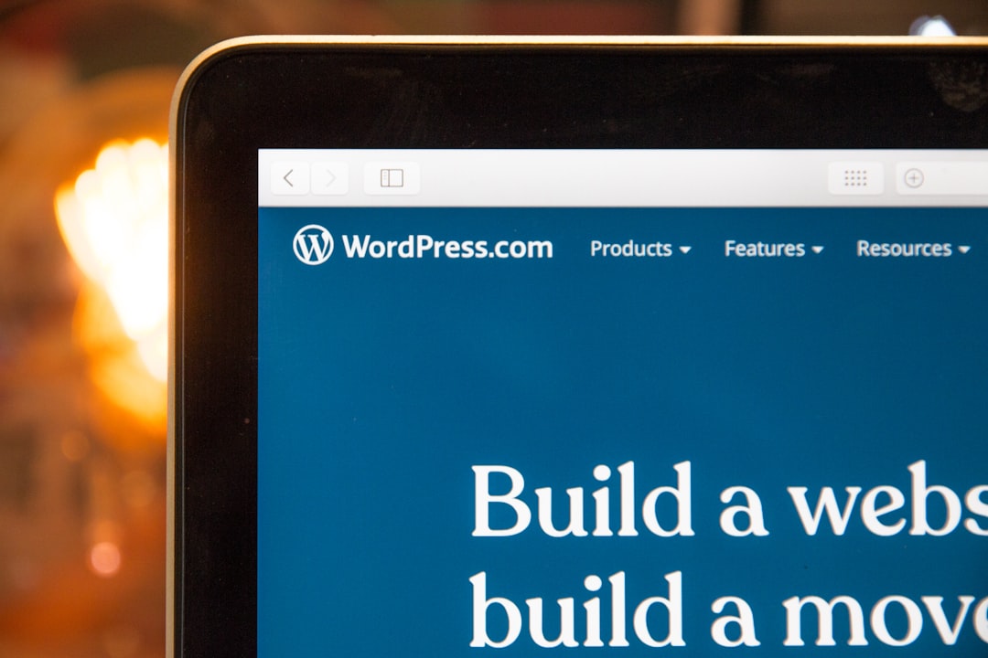 Laptop screen showing WordPress.com homepage with blue navigation bar and a large white 'Build a website' headline on a blue background.