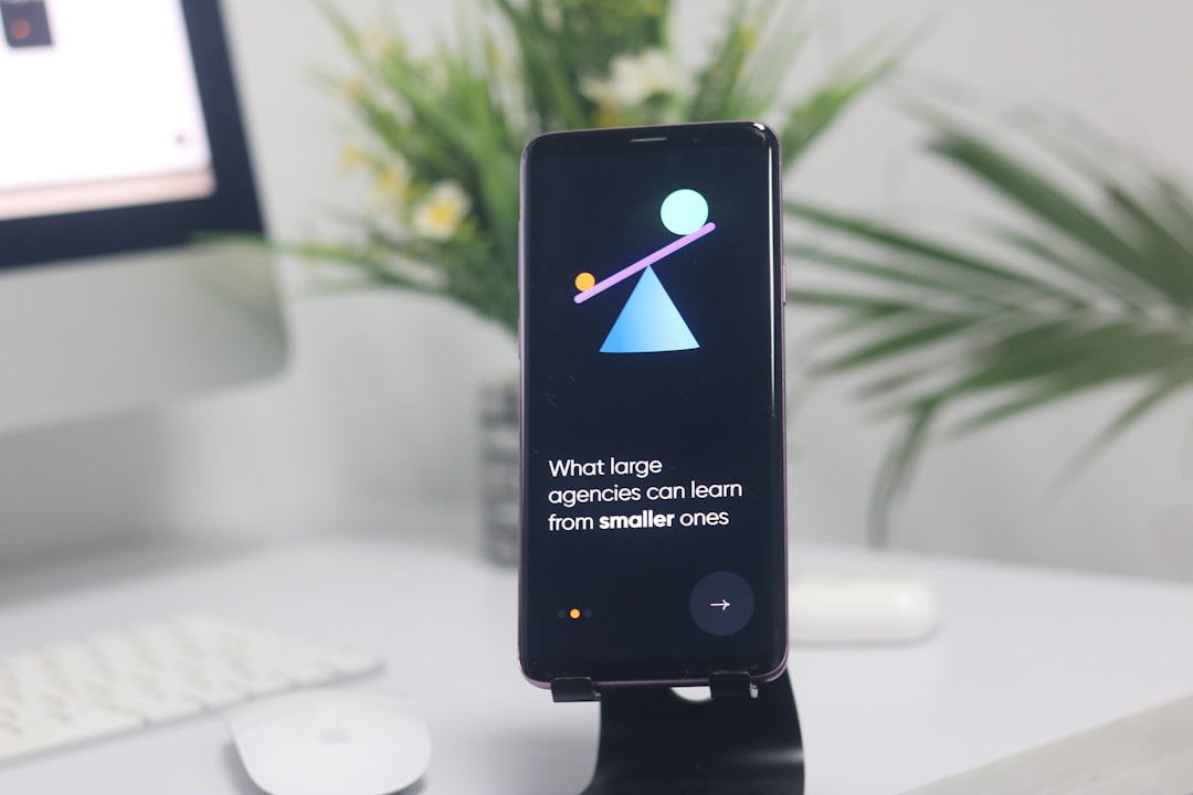 Smartphone on a stand showing an onboarding slide with abstract shapes and the text "What large agencies can learn from smaller ones"