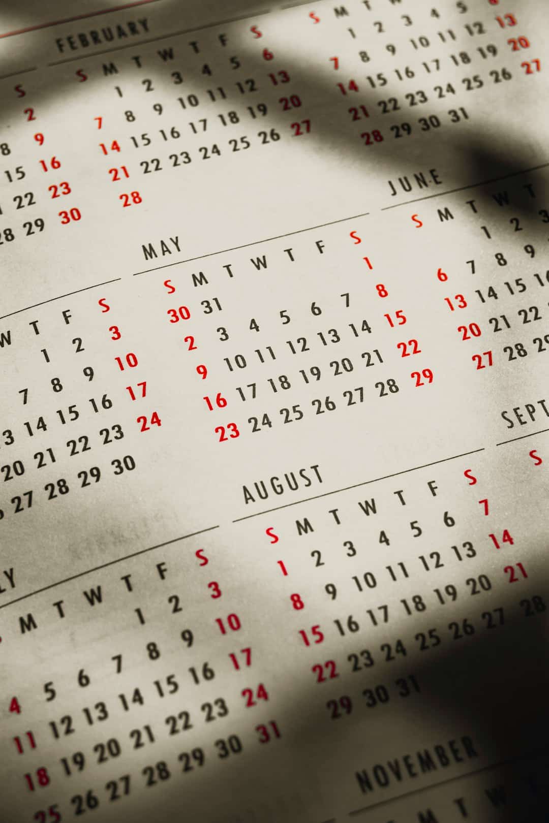 Close-up of a vintage desk calendar page showing May, June, August, and November with red weekend dates.