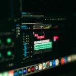 Video editing timeline with colorful tracks on a dark monitor, editing software in use.