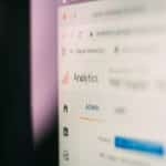 Close-up of a blurred analytics dashboard showing the word Analytics and an Admin panel in the left navigation.
