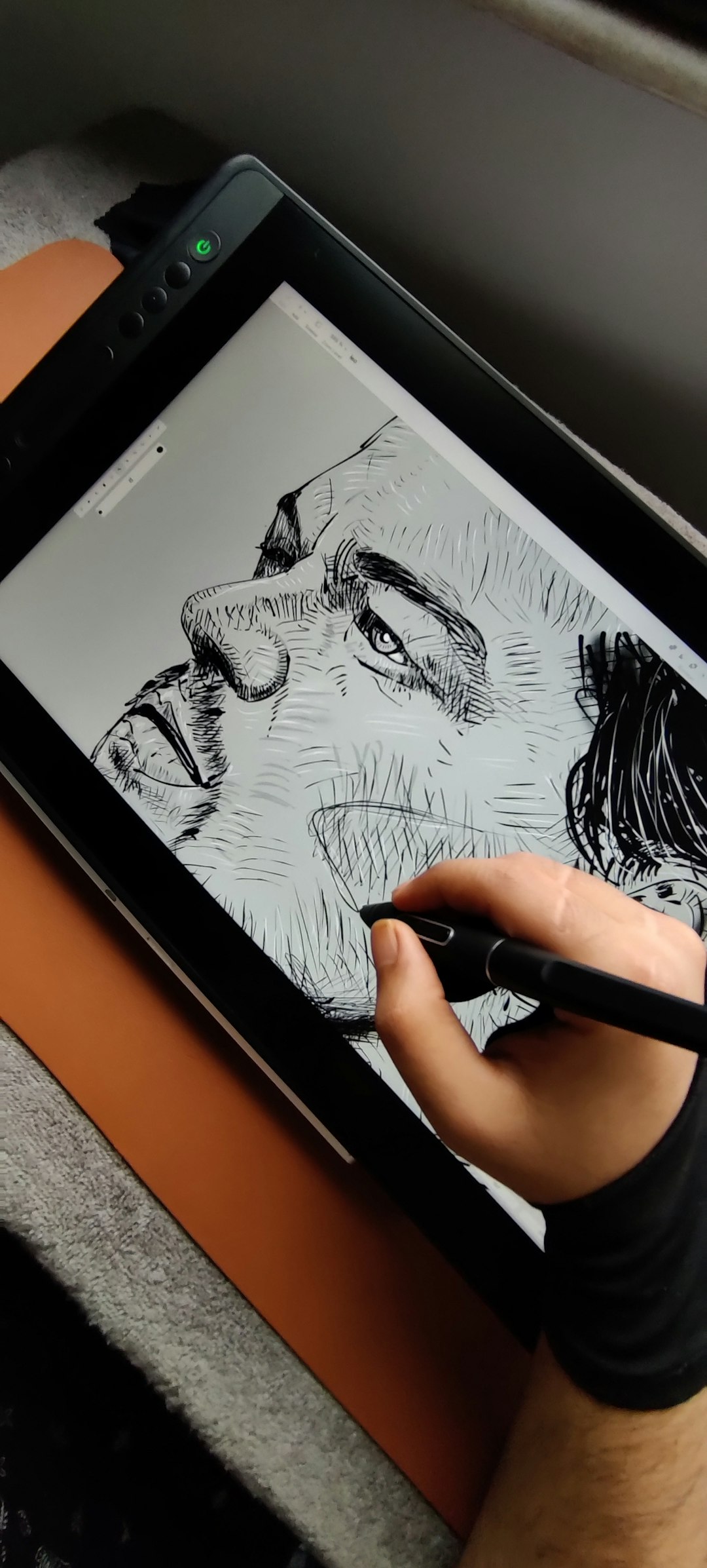 A hand holds a stylus drawing a detailed black-and-white portrait on a tablet screen.