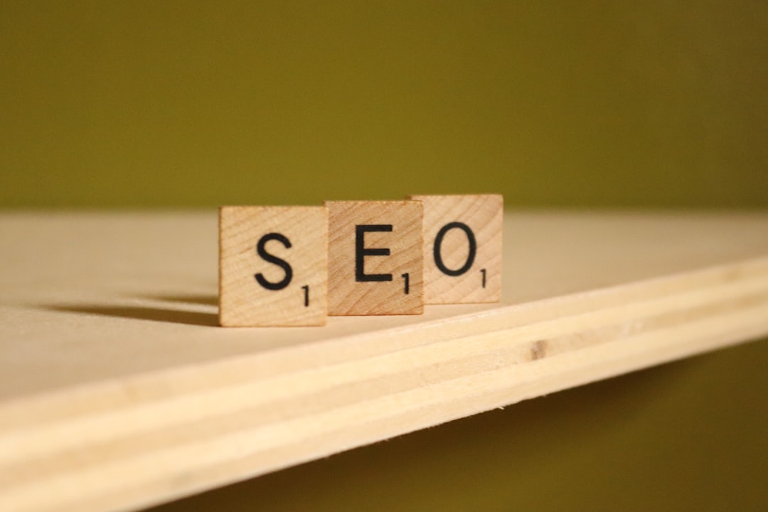 Three wooden letter tiles spell 'SEO' on a light wood surface with a warm, blurred background.