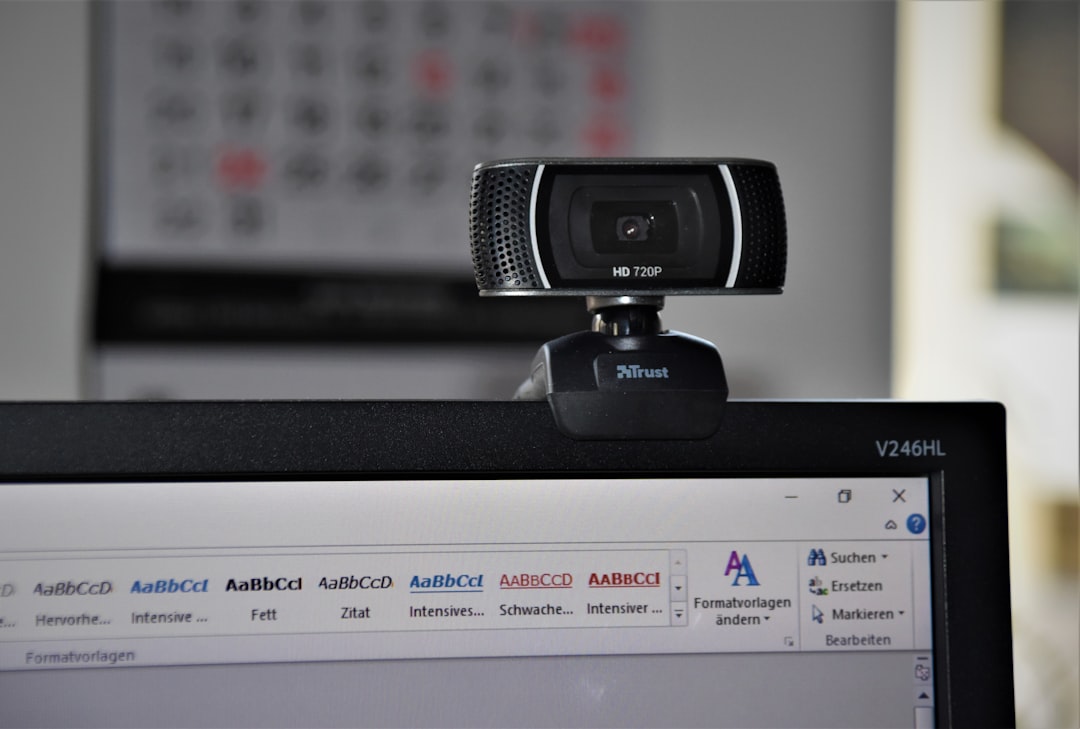 Webcam mounted on top of a computer monitor over a Word document on screen (office setup).