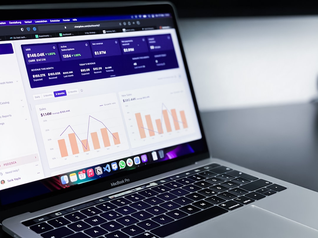 MacBook Pro displaying a data analytics dashboard with bar and line charts in orange and purple tones.