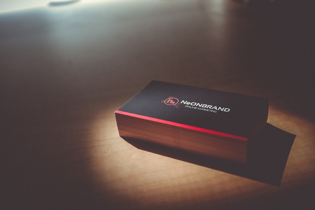 Black business card box with a red edge on a wooden table, logo reads NEONBRAND Online Marketing.