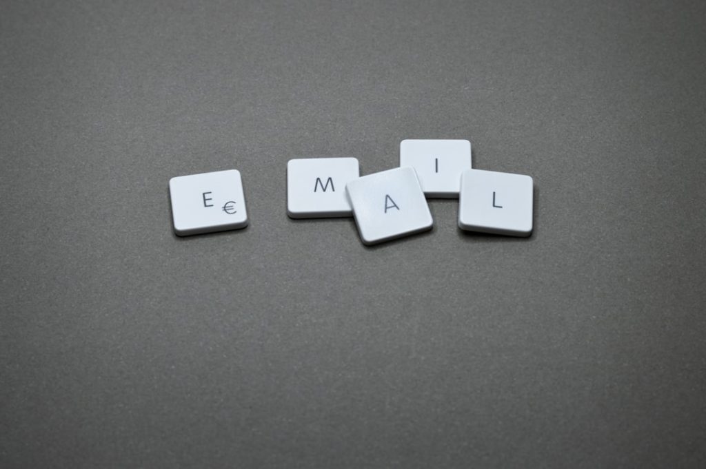White square keyboard keys arranged to spell the word EMAIL on a gray surface.