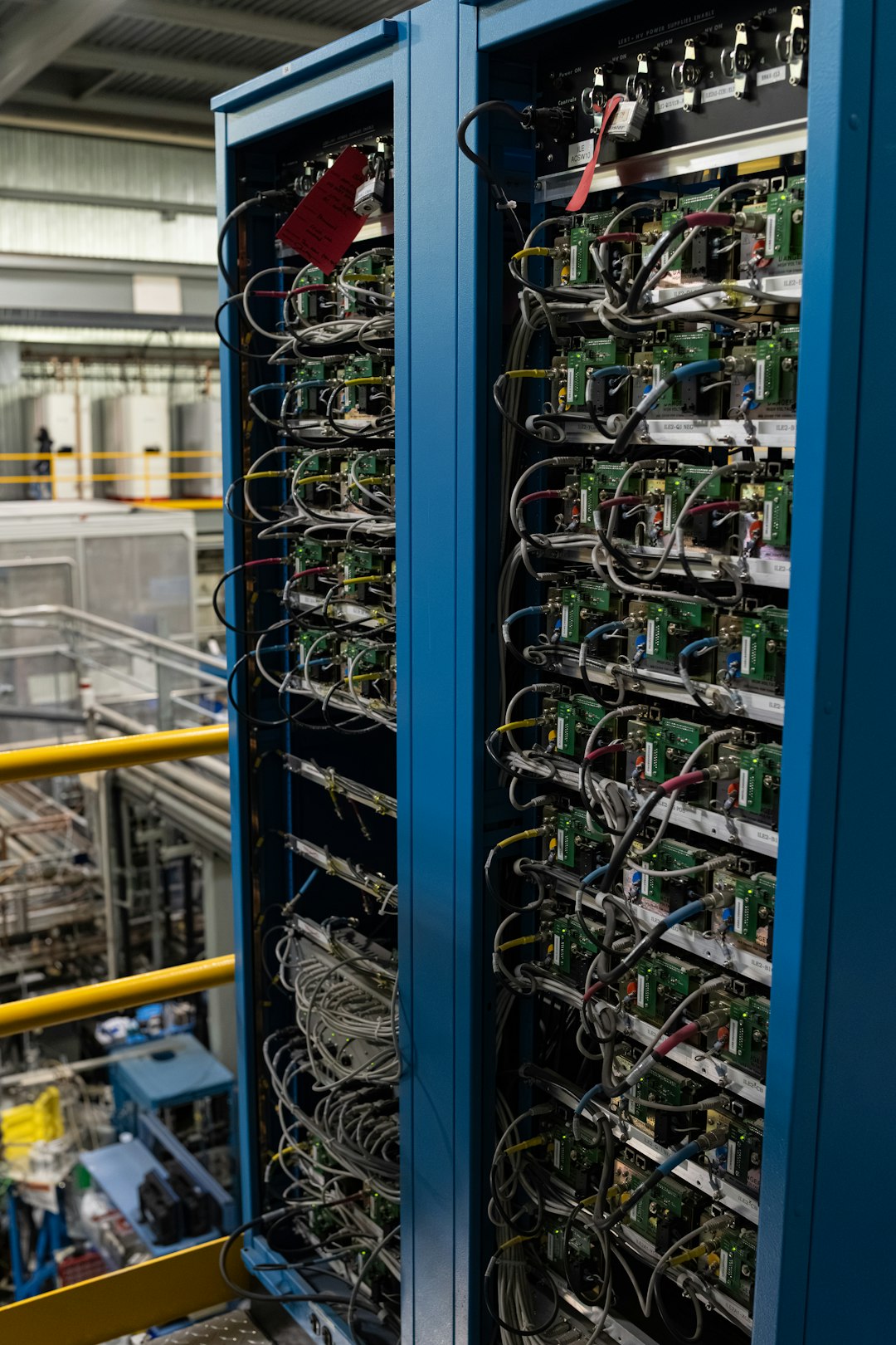 Blue server rack housing densely wired control boards and cables in an industrial data center, conveying complex electronic infrastructure.