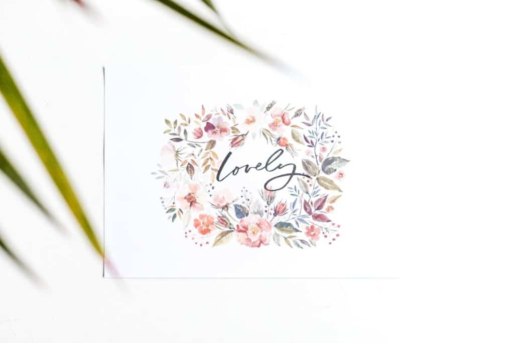 Card with a watercolor floral wreath surrounding the word 'lovely' in cursive on a white background
