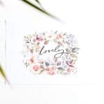 Card with a watercolor floral wreath surrounding the word 'lovely' in cursive on a white background