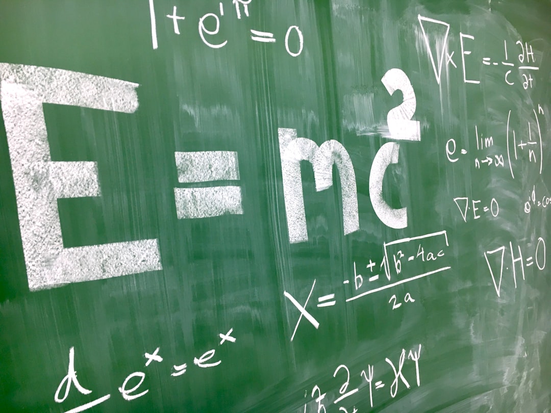 Green chalkboard filled with white physics equations, prominently showing Einstein's E=mc^2.