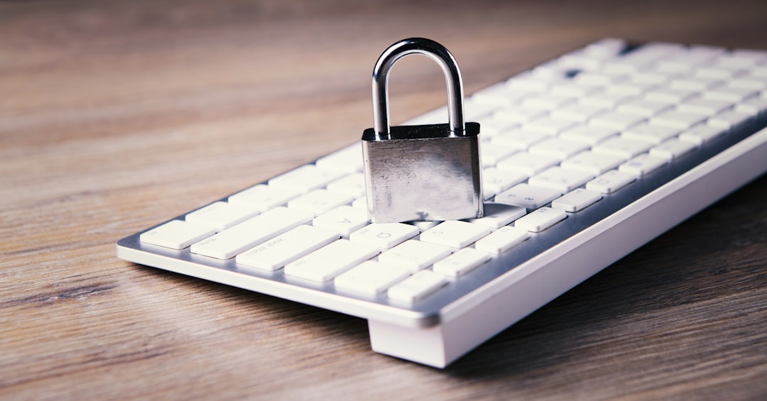 Padlock resting on a white keyboard, symbolizing computer security and data protection on a wooden desk.