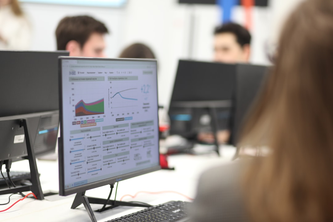 Desk setup in an office with a monitor showing a dashboard of charts and graphs on the screen