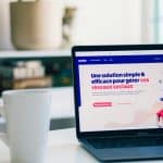 Laptop on a white desk showing a French marketing webpage about social networks in bold blue and pink text.